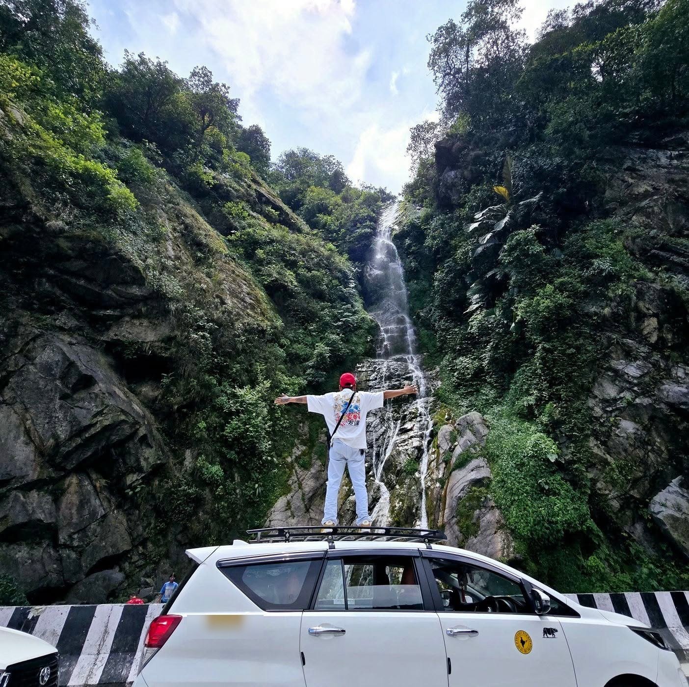 Traveller at a roadside waterfall with tour vehicle in Arunachal Pradesh